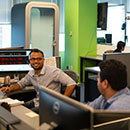 Two men sitting at desks smiling and talking